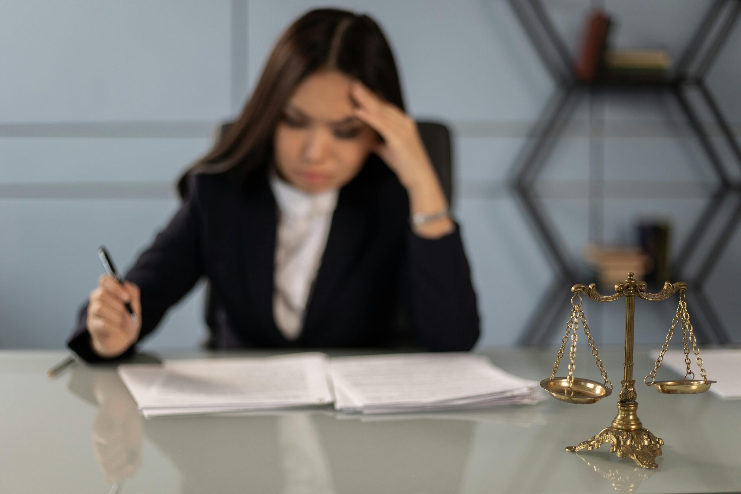 A stressed female lawyer sitting at her desk, scratching her head while reviewing her annual penetration test report, with golden legal scales in the foreground, symbolising the pressure legal firms face under rising cybersecurity threats and the dangers of falling into the pentest trap.