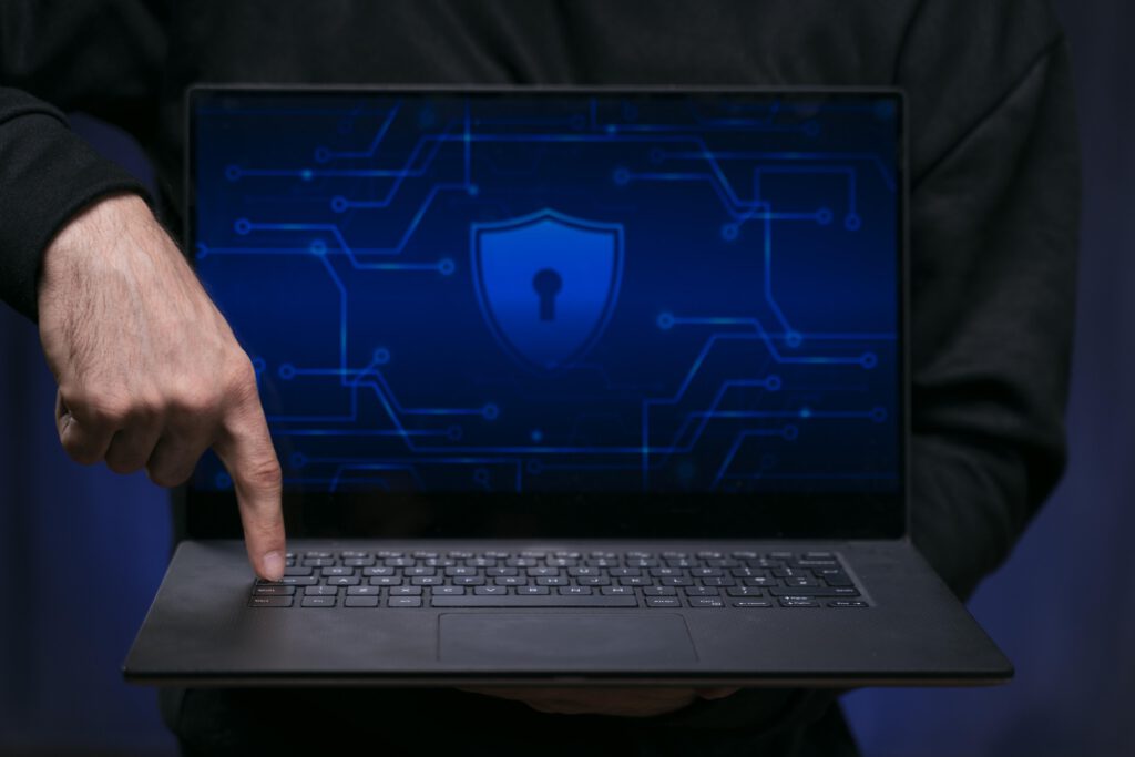 Close up of a finger pressing a button on a laptop with a padlock on the screen to start vulnerability assessments.